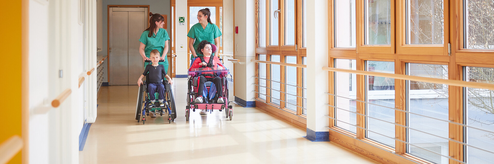 Bild: Zwei Pflegefachkräfte der Kinderklinik Schömberg schieben zwei Kinder in Rollstühlen
