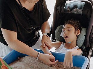 Kind mit Mutter an einer Spielkiste mit Sand auf dem Sommerfest der Kinderklinik Schömberg 2026