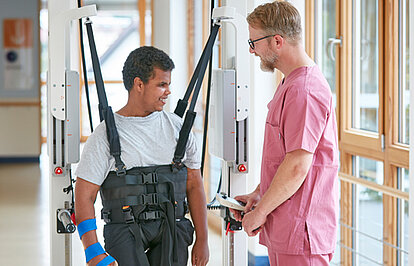Picture: A therapist and a patient doing gait training in the Innowalk. The picture is linked to the section Therapeutic Focuses