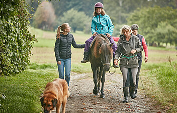 Picture: Patient accompanied by a therapist and relatives on the swaying back of a horse