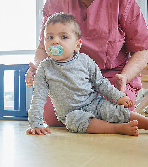 Bild: Um ein individuelles Entwicklungskonzept zu erstellen, testet eine Physiotherapeutin die Motorik eines Kleinkindes.