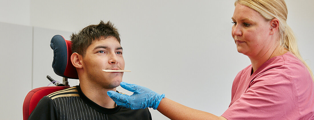 Bild: Eine Logopädin trainiert durch spezielle Übungen mit einem Holzspatel die Mundmuskulatur eines Jungen