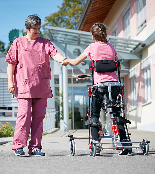 Picture: With an individually adapted walking aid and the help of a therapist, the patient takes her first steps.