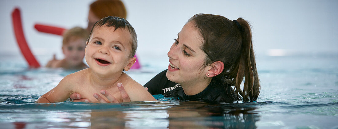 Bild: Ein kleines Kind mit seiner Therapeutin entspannt und bewegt sich im warmen Wasser