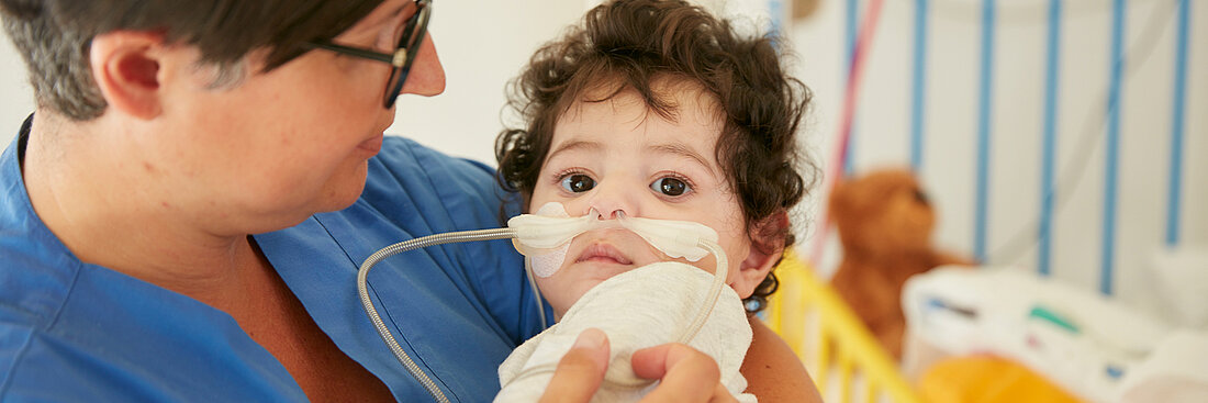 Bild: Die Atmungstherapeutin der Kinderklinik hält ein beatmetes Kind auf dem Arm