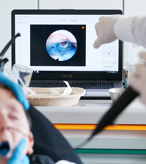 Bild: Ein Arzt kontrolliert mit einem Endoskop über die Nase des Patienten die Funktion des Schluckaktes