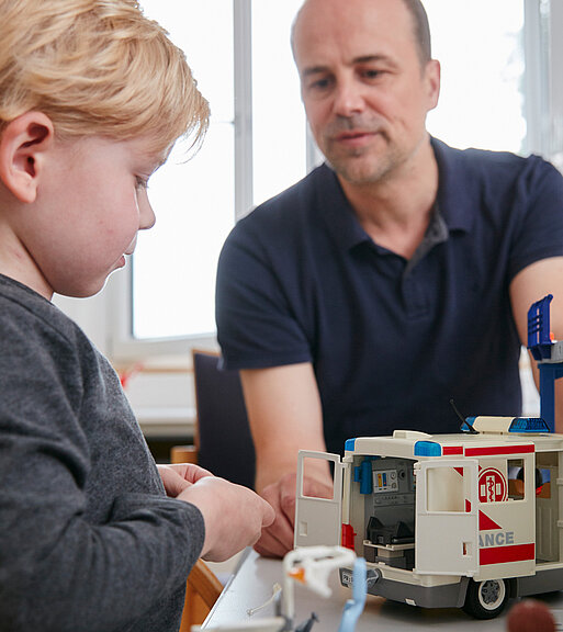 Bild: Mit Hilfe eines Spielzeugautos nimmt der Psychologe den Kontakt zum Patienten auf