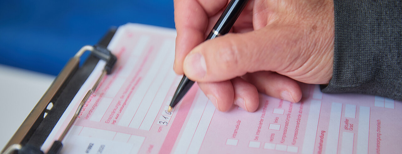 Help with applications Image: Hand holding a pen and filling out an application
