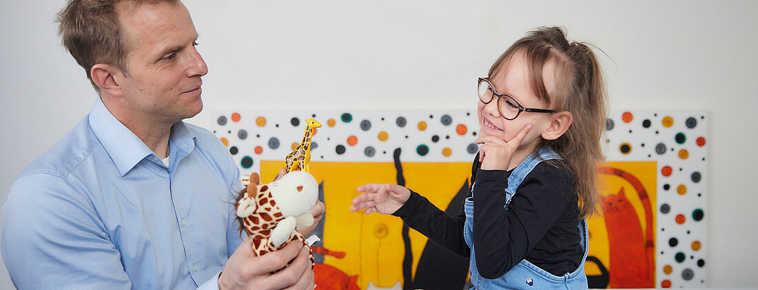 Picture: A doctor playfully diagnoses the neurological development status of a small patient with two stuffed animals. 