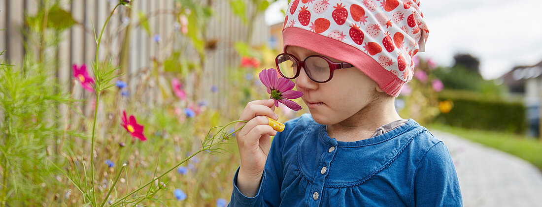 Bild: Ein Kind riecht im Garten der Kinderklinik an einer Blume