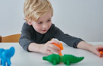 Bild: Ein Kind versucht Einzelteile zu kompletten Spielzeugtieren zusammenzufügen