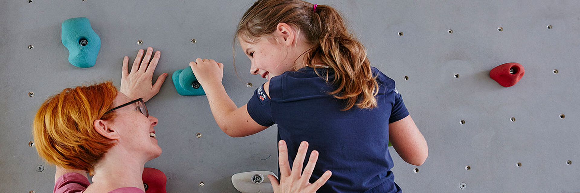 Physiotherapie an der Kletterwand, Therapeutin mit Kind in der Kinderklinik Schömberg
