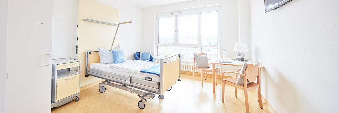 Bild: Einzelzimmer in der Kinderklinik Schömberg. Helles freundliches Ambiente mit Bett Tisch und Stühlen