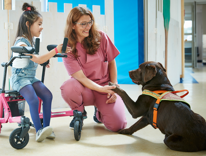Bild: Die kleine Patientin und Ihre Therapeutin lassen Therapiehund Fanny Pfötchen geben