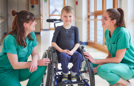 Communication with the patients Picture: Two therapists take care of a boy in a wheelchair
